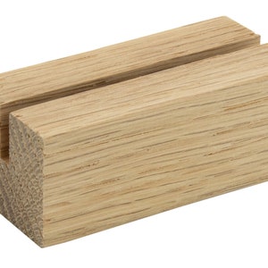 May include: A wooden sign holder with a slot for displaying a card or sign. The holder is made of natural wood with a light brown color.