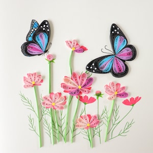 May include: Paper craft of two butterflies with pink and blue wings and a field of pink cosmos flowers.