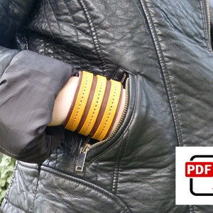 May include: A person wearing a black leather jacket with a yellow and brown leather bracelet on their wrist.
