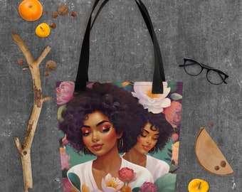 May include: A tote bag with a colorful floral design featuring two women with dark brown hair and skin. The women are surrounded by pink, white, and green flowers.