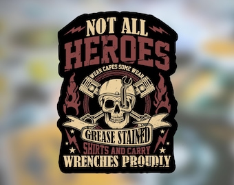 May include: A black sticker with the text "NOT ALL HEROES WEAR CAPES SOME WEAR GREASE STAINED SHIRTS AND CARRY WRENCHES PROUDLY." The design features a skull wearing a helmet with a wrench and crossed pistons.