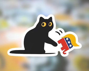 May include: A black cat sticker with yellow eyes, swatting at a cartoon elephant with a yellow toupee, red body, and blue stars. The sticker has a white border and is on a blurred background.