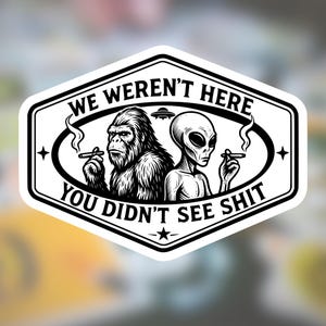 May include: A black and white sticker featuring a graphic illustration of Bigfoot and an alien, both smoking cigars. Above them is a small UFO, and the text reads WE WEREN'T HERE and YOU DIDN'T SEE SHIT, all enclosed within a hexagonal border.