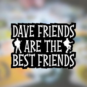 May include: A black rectangular sticker with white text that reads DAVE FRIENDS ARE THE BEST FRIENDS. The design includes two white silhouettes of people playing acoustic guitars, one on the left and one on the right side of the text.