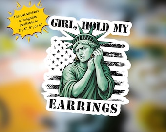 May include: A sticker featuring a green Statue of Liberty holding her ear with a distressed look. The background is a black and white American flag. The text "GIRL, HOLD MY EARRINGS" is written in white letters on a black background.