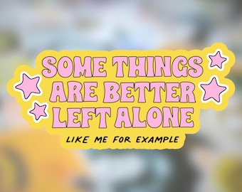 Könnte beinhalten: Ein gelber Aufkleber mit dem Text "SOME THINGS ARE BETTER LEFT ALONE LIKE ME FOR EXAMPLE" in rosa Buchstaben. Rosa Sternformen befinden sich auf der linken und rechten Seite des Aufklebers.