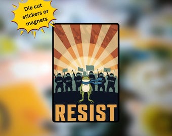 May include: A rectangular sticker or magnet featuring a cartoon frog wearing a blue scarf, standing in front of a group of police officers. The word "RESIST" is printed in bold letters at the bottom. The background has a retro design with orange and brown rays.