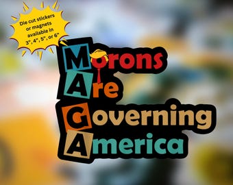 May include: A sticker with the text "Morons Are Governing America" in colorful block letters. The "M" in "Morons" is a red block with a yellow cartoon figure wearing a red tie. The sticker is available in sizes 3, 4, 5, or 6 inches.