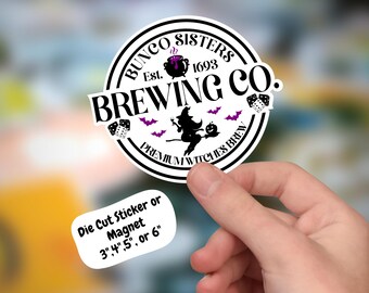 May include: A white circle sticker with black text that reads "Bunco Sisters Est. 1693 Brewing Co. Premium Witches Brew". The sticker features a black and white illustration of a witch flying on a broomstick with a cauldron and bats. The sticker is available in 3, 4, 5, or 6 inch sizes.