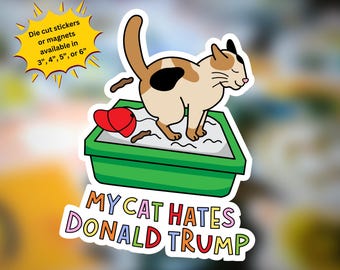 May include: A die-cut sticker featuring a calico cat in a green litter box with a red cap inside. The text reads: Die cut stickers or magnets available in 3", 4", 5", or 6" and MY CAT HATES DONALD TRUMP in colorful letters below the litter box.
