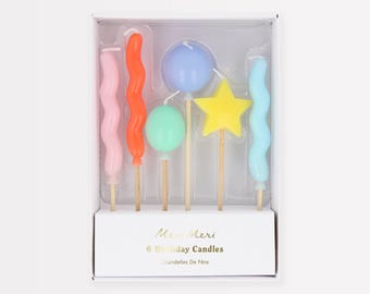 May include: A box set of six colorful birthday candles. The candles are in various shapes, including wavy, spherical, and star-shaped, in shades of pink, orange, blue, green, and yellow. The box has the text "Meri Meri 6 Birthday Candles".