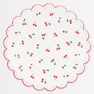 May include: A round, white paper plate with a scalloped edge and a red border. The plate is decorated with a pattern of red cherries and green leaves.