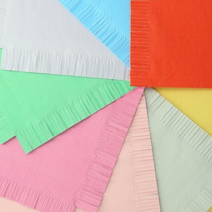 May include: A set of eight colorful napkins with fringed edges. The napkins are arranged in a circle, with the colors alternating from light to dark. The colors are white, light blue, orange, green, pink, light pink, light green, and yellow.