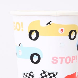 May include: White paper cups with a racing car theme. The cups feature yellow, blue, and red cars with the words "GO!" and "STOP!" printed on them.
