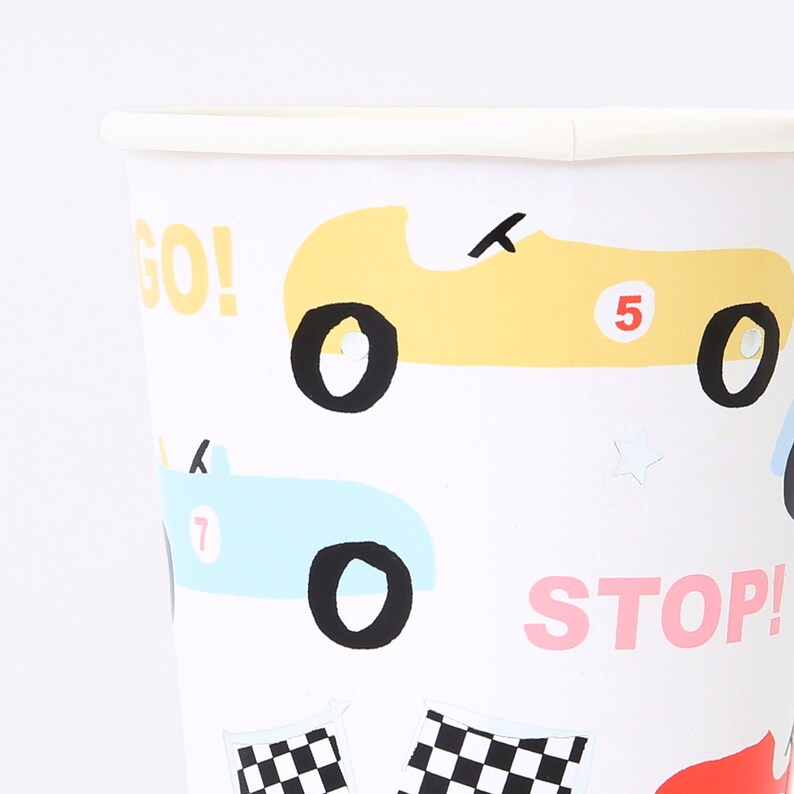 May include: White paper cups with a racing car theme. The cups feature yellow, blue, and red cars with the words "GO!" and "STOP!" printed on them.