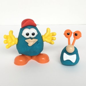 May include: Two blue Play-Doh figures with orange and yellow accents. One figure has a red hat and the other has two large orange eyes.