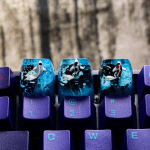 May include: Three custom keyboard keycaps with koi fish designs. Each keycap features a different koi fish, set against a blue and black water-like background. The keycaps are mounted on a purple keyboard.