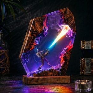 May include: A decorative lamp featuring a wooden frame with embedded purple and orange resin. A miniature figure holding a minigun is positioned inside, with a bright light effect emitting from the weapon barrel, creating a vibrant display.