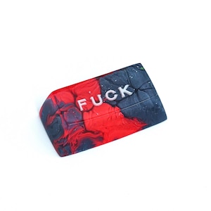 May include: A rectangular object with a marbled effect, featuring the word "FUCK" in silver lettering. The design is split, with red on one side and black and grey swirls on the other. The object is set against a white background.