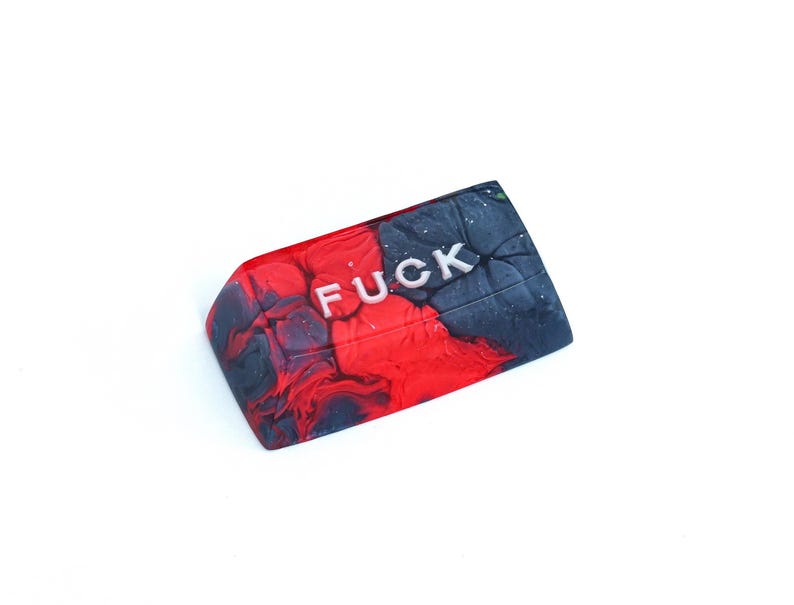 May include: A rectangular object with a marbled effect, featuring the word "FUCK" in silver lettering. The design is split, with red on one side and black and grey swirls on the other. The object is set against a white background.