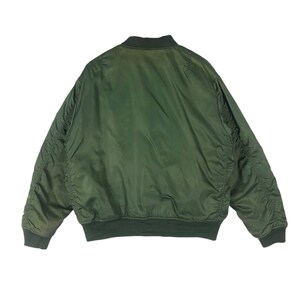 May include: A green bomber jacket with a ribbed collar, cuffs, and hem. The jacket has a smooth, shiny texture and a classic bomber silhouette. The back view shows the full shape of the jacket.