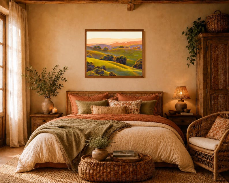 Peut inclure: Une peinture de paysage rectangulaire dans un cadre en bois brun repr&eacute;sentant des collines verdoyantes avec des arbres &eacute;pars sous un ciel de coucher de soleil chaud. L'&oelig;uvre est expos&eacute;e sur un mur beige au-dessus d'un lit aux tons rouille et olive.