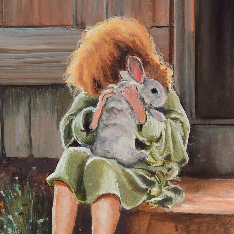 May include: A young person with long, red hair is holding a white rabbit close to their chest. The person is wearing a green robe and is sitting on a wooden step.