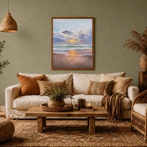 May include: A rectangular framed painting depicting a coastal sunset scene with soft clouds, a calm ocean, and a sandy beach. The artwork features a palette of light blue, soft pink, and golden yellow tones, displayed in a simple wooden frame.