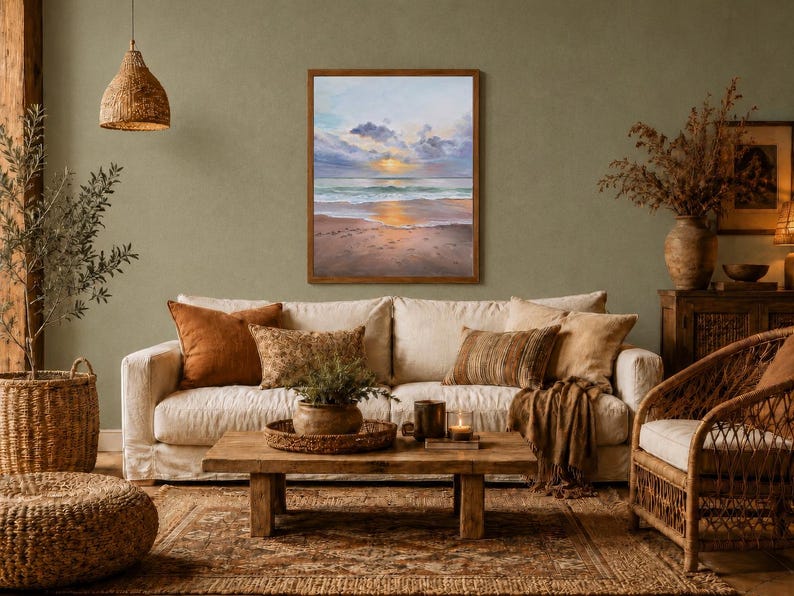 May include: A rectangular framed painting depicting a coastal sunset scene with soft clouds, a calm ocean, and a sandy beach. The artwork features a palette of light blue, soft pink, and golden yellow tones, displayed in a simple wooden frame.