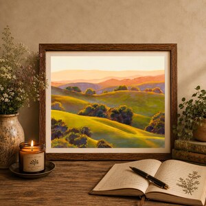 Peut inclure: Une peinture de paysage encadr&eacute;e repr&eacute;sentant des collines verdoyantes et des montagnes lointaines sous un ciel de coucher de soleil chaud. L'&oelig;uvre est pos&eacute;e sur une surface en bois avec une bougie allum&eacute;e, une plante et un livre ouvert avec un stylo.