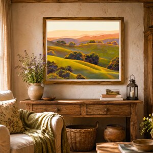 Peut inclure: Une peinture de paysage encadr&eacute;e repr&eacute;sentant des collines verdoyantes, des arbres &eacute;pars et des montagnes lointaines sous un ciel aux teintes dor&eacute;es. L'&oelig;uvre est expos&eacute;e sur un mur textur&eacute; au-dessus d'une console en bois.