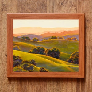 Peut inclure: Une peinture de paysage encadr&eacute;e repr&eacute;sentant des collines verdoyantes sous un ciel de coucher de soleil doux. La sc&egrave;ne pr&eacute;sente des groupes d'arbres vert fonc&eacute; dispers&eacute;s sur les pentes, avec des montagnes orange et violettes au loin. La signature SEYMER est visible.