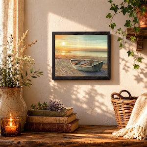 Op de afbeelding: Een ingelijste kunstdruk met een kleine roeiboot op een zandstrand bij zonsondergang. De sc&egrave;ne toont een rustige oceaanhorizon onder een zachte gouden lucht, met de boot op de voorgrond. Het kunstwerk is geplaatst in een donkere lijst.