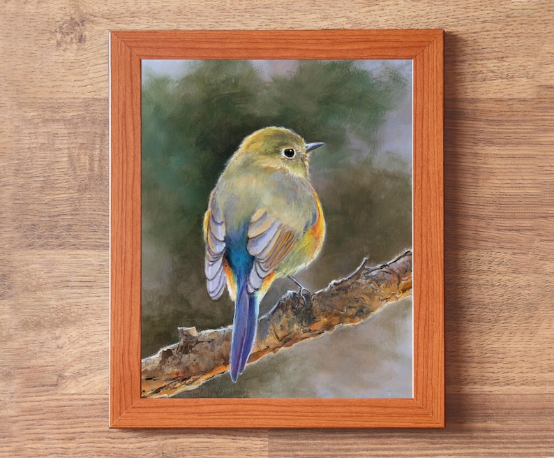 May include: A framed print featuring a painting of a small bird with olive-green, yellow, and blue feathers perched on a textured brown tree branch. The bird is shown from behind, looking to the right. The frame is made of light brown wood.
