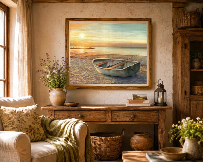 Op de afbeelding: Een ingelijst landschapsschilderij met een kleine roeiboot op een zandstrand bij zonsondergang. De sc&egrave;ne toont een kalme oceaan, een zachte gouden lucht en een houten boot met roeispanen. Het kunstwerk is geplaatst in een rustieke houten lijst.