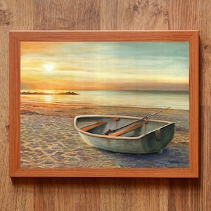 Op de afbeelding: Een ingelijst schilderij met een kleine roeiboot op een zandstrand bij zonsondergang. De sc&egrave;ne toont een kalme oceaan, een felle zon laag aan de horizon en zacht goudkleurig licht dat reflecteert op het water en de houten bankjes in de boot.