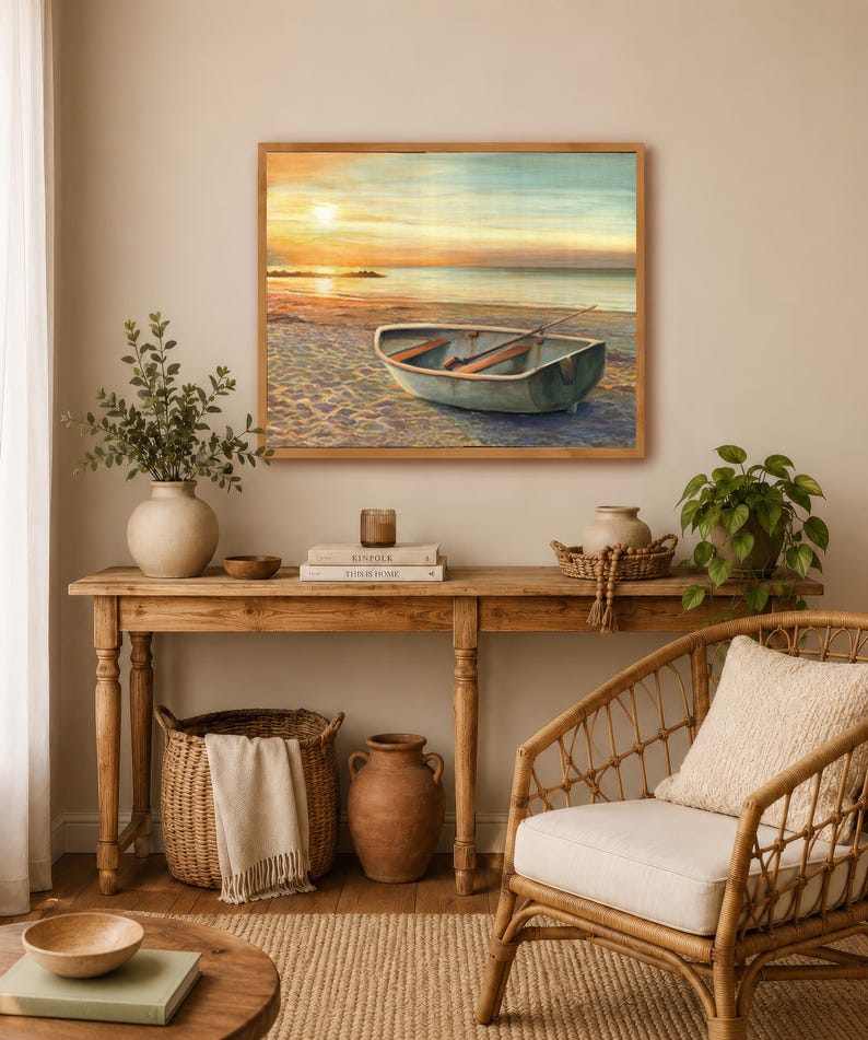 Op de afbeelding: Een rechthoekige ingelijste wandkunstprint met een kleine roeiboot op een zandstrand bij zonsondergang. Het schilderij toont een kalme oceaanhorizon, een zachte gouden lucht en een boot met houten roeispanen in een lichtgekleurde houten lijst.