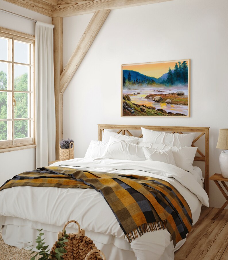 May include: A rectangular landscape painting in a light wood frame depicting a river flowing through a misty valley at sunrise. The scene features dark green pine trees, rocky riverbanks, and a golden sky reflecting on the water surface.