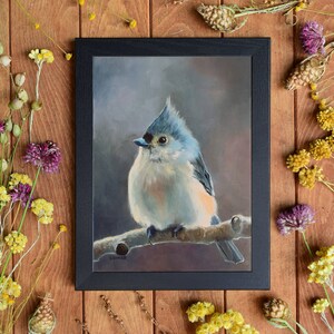 May include: A painting of a tufted titmouse perched on a branch. The bird is painted in shades of blue, gray, and white, with a hint of orange on its breast. The background is a soft, muted gray.
