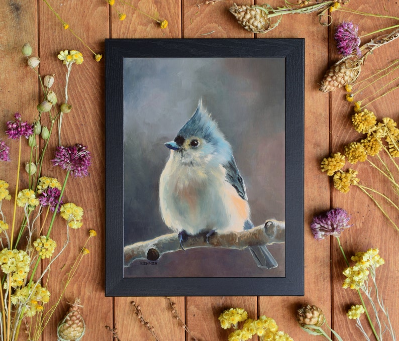 May include: A painting of a tufted titmouse perched on a branch. The bird is painted in shades of blue, gray, and white, with a hint of orange on its breast. The background is a soft, muted gray.