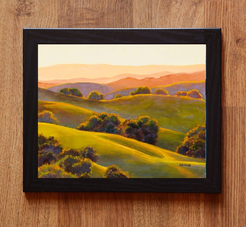 Peut inclure: Une peinture de paysage dans un cadre noir repr&eacute;sentant des collines verdoyantes avec des arbres sombres dispers&eacute;s sous un ciel aux tons chauds. L'&oelig;uvre pr&eacute;sente des silhouettes de montagnes en arri&egrave;re-plan et la signature SEYMER en bas.