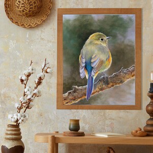 May include: A framed wall art print featuring a detailed painting of a small bird with yellow, green, and blue plumage perched on a textured tree branch against a soft, dark green background. The frame is made of light brown wood with a simple finish.
