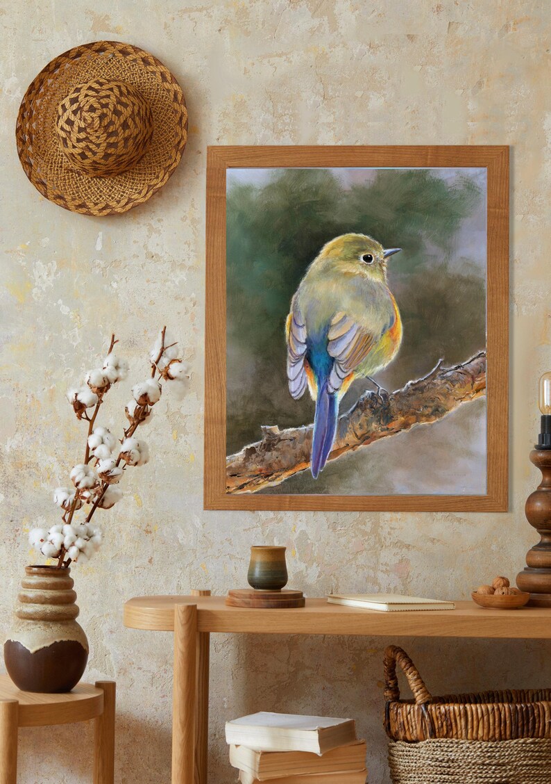 May include: A framed wall art print featuring a detailed painting of a small bird with yellow, green, and blue plumage perched on a textured tree branch against a soft, dark green background. The frame is made of light brown wood with a simple finish.