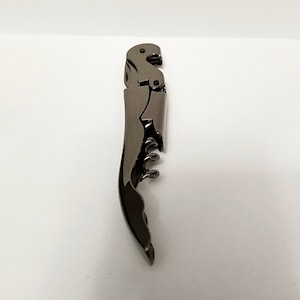 May include: A silver-colored metal corkscrew with a lever and a worm.