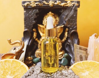 May include: A gold bottle with a dropper, labeled "Love", sits on a gray rock surrounded by orange slices, green stones, and mint leaves. The bottle is in front of a black and gold statue and a white candle.