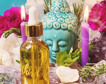 Puede incluir: Una botella de vidrio transparente con tapa dorada y gotero llena de un líquido amarillo. La botella está etiquetada con "Third Eye". La botella está rodeada de cristales, velas y vegetación.
