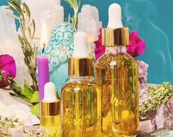 Puede incluir: Tres botellas de vidrio con tapas doradas y goteros llenos de un líquido amarillo. Las botellas están etiquetadas con "tercer ojo" y "ritual del tercer ojo". Las botellas están sobre una mesa con cristales y otros artículos decorativos.