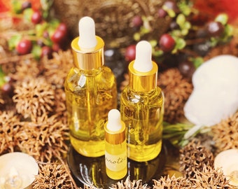 May include: Three glass bottles with gold caps and droppers filled with a clear yellow liquid. The bottles are sitting on a tray with brown, spiky, dried plant material.