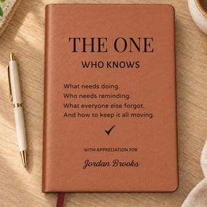May include: A brown leather-bound notebook featuring the black printed text THE ONE WHO KNOWS, followed by a list of tasks, a checkmark, and the text WITH APPRECIATION FOR Jordan Brooks, accompanied by a white and gold ballpoint pen.