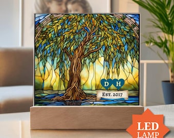 Pode incluir: Uma luminária quadrada em estilo vitral apresentando um salgueiro com folhas verdes e amarelas sobre um fundo azul e amarelo. Dois corações azuis com as letras D e H são exibidos acima de uma faixa com o texto EST. 2017.